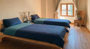 a bedroom with two beds with blue sheets and a window at Gîte du Gacet in Trévérien +2 photos