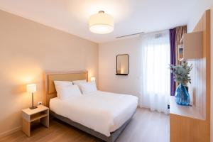 a bedroom with a white bed and a window at Quality Aparthotel Villefontaine in Villefontaine +22 photos