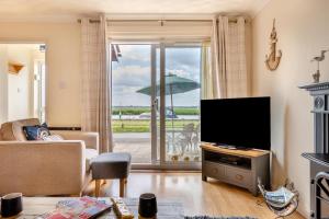 a living room with a television and a view of a patio at 2 Bed in Reedham oc-c29528 in Haddiscoe