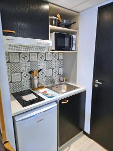 a small kitchen with a sink and a microwave at [Chalet] Studio Premium, WIFI, Chaleureux in Lourdes +15 photos