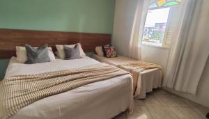 a hotel room with two beds and a window at Casa Espaço Pérola in Rio das Ostras