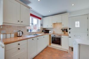 a white kitchen with white cabinets and a sink at 3 Bed in Westleton oc-swc in Westleton +6 photos