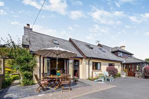 a house with an umbrella and a table and chairs at 2 Bed in Aberystwyth oc-99869 in Devils Bridge