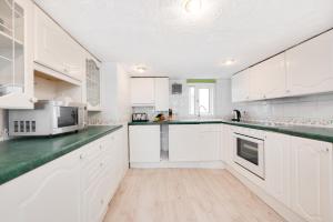 a white kitchen with white cabinets and green counter tops at 3 Bed in St Ives oc-pc1016 in St Ives +6 photos