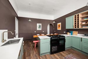a kitchen with green cabinets and a black stove at 6 Howard Place in St. Andrews