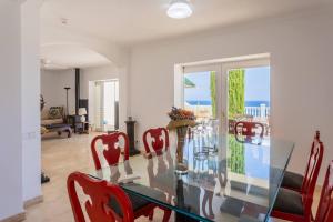 a dining room with a glass table and red chairs at Villa Acantilado Cabo de Palos in Cabo de Palos