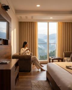 a woman sitting in a chair in a hotel room at Hotel Chail Residency in Chail