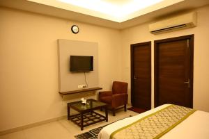 a bedroom with a bed and a chair and a tv at TTAMAASHA INNN in Chinhat