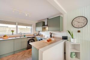 a kitchen with green cabinets and a clock on the wall at 3 Bed in Croyde oc-f33111 in Croyde