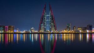 a city skyline with a tall building at night at Bab Al Bahrain Hotel in Manama +19 photos