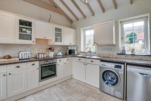 a kitchen with white cabinets and a washer and dryer at 2 Bed in Llanmadoc oc-hh469 in Llanmadoc +18 photos