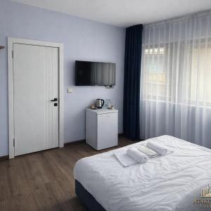 a bedroom with a white bed and a television at ATAKORU Suit in Alacaatlı