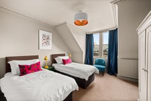 a bedroom with two beds and a blue chair at 6 Howard Place in St. Andrews