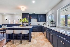 a kitchen with blue cabinets and a large island with bar stools at LWV Dallas Social - Lakewood Village in Little Elm
