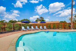 a swimming pool with chairs and blue umbrellas at LWV Dallas Social - Lakewood Village in Little Elm
