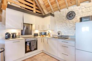 a kitchen with white cabinets and a clock on the wall at 2 Bed in Clevedon oc-t30786 in Clevedon
