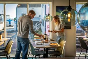 a man and woman standing around a table with pizza at Hotel Aurora in Nuuk
