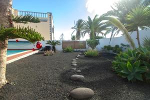 a garden with rocks and trees and a pool at Niteo House in Costa Teguise