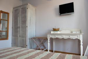a bedroom with a white table and a tv on a wall at Zorbas Apartments in Volissos