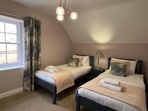 two beds in a room with a window at Bleaton Hallet House Riverside Escape in Kingseat