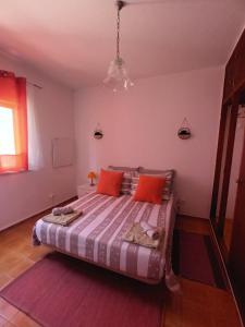 a bedroom with a large bed with orange pillows at Casa marreiros in Aljezur