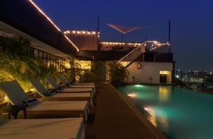 a hotel swimming pool with chaise lounge chairs at night at Lao Poet Hotel in Vientiane
