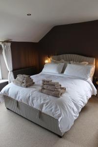 a bedroom with a white bed with towels on it at Plum Cottage in Cottesmore