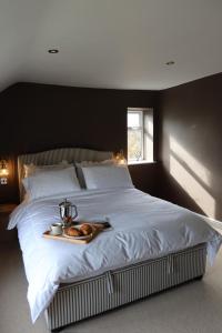 a large bed with a tray of bread on it at Plum Cottage in Cottesmore