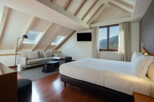 a bedroom with a large white bed and a couch at Hotel de l'Isard in Andorra la Vella