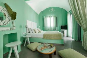 a green bedroom with a bed and a table at Santorini Roses Suites in Imerovigli