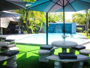 a table and chairs with umbrellas next to a pool at Haleys Guest House in Benoni