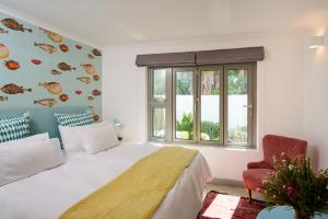 a bedroom with a bed and a window and a chair at ocean10 Guesthouse in Cape Town