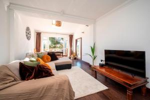 a living room with a couch and a flat screen tv at Spacious 4Bed Home with Decked Garden Forest Hill - Pass the Keys in London