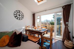 a living room with a table and a clock on the wall at Spacious 4Bed Home with Decked Garden Forest Hill - Pass the Keys in London