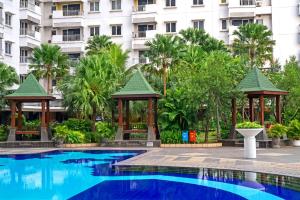 a swimming pool with gazebos in front of a building at Grand Whiz Poins Simatupang Jakarta in Jakarta
