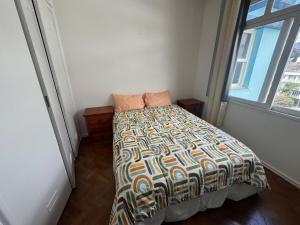 a bedroom with a bed with a comforter and a window at Apartamento alto de Teresópolis in Teresópolis