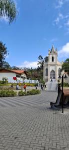 a large white building with a church in the background at Aconchego - Centro in Miguel Pereira