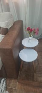 a couch with two tables and a vase with flowers on it at Aconchego - Centro in Miguel Pereira +11 photos