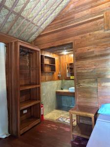 a bathroom with wooden walls and a bed and a sink at Camp Olli Beach Villas in Dapa