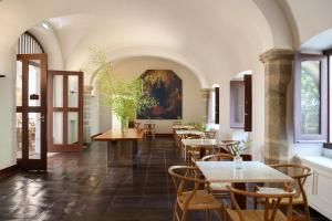 a restaurant with tables and chairs and a painting on the wall at Convento do Espinheiro, Historic Hotel & Spa in Évora