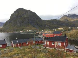 a village with red houses and a mountain at Buodden Rorbuer - Fisherman Cabins Sørvågen in Sørvågen