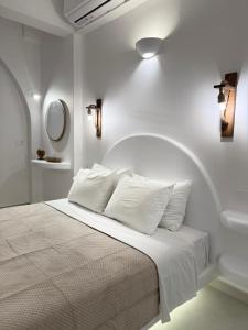 a white bedroom with a bed with white pillows at Seaside by Manos in Kamari