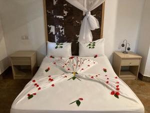 a bedroom with a white bed with flowers on it at KC Bungalows in Nungwi