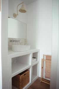 a white bathroom with a sink and a basket at OKTO Beach Loft in Praia do Almoxarife