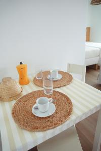 a table with two cups and saucers on it at OKTO Beach Loft in Praia do Almoxarife
