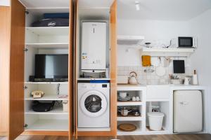 a small kitchen with a washing machine in a closet at OKTO Beach Loft in Praia do Almoxarife +21 photos