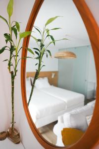 a mirror with a plant and a bed in a room at OKTO Beach Loft in Praia do Almoxarife