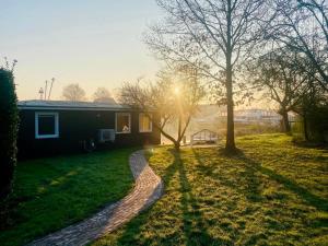 a house with the sun shining on the grass at Houseboat Sneek in Sneek