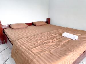 a bed in a bedroom with a brown comforter at Nerly's Panorama in Bukit Lawang