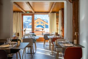 a restaurant with tables and chairs and a large window at Hotel & Spa Merilys in Méribel